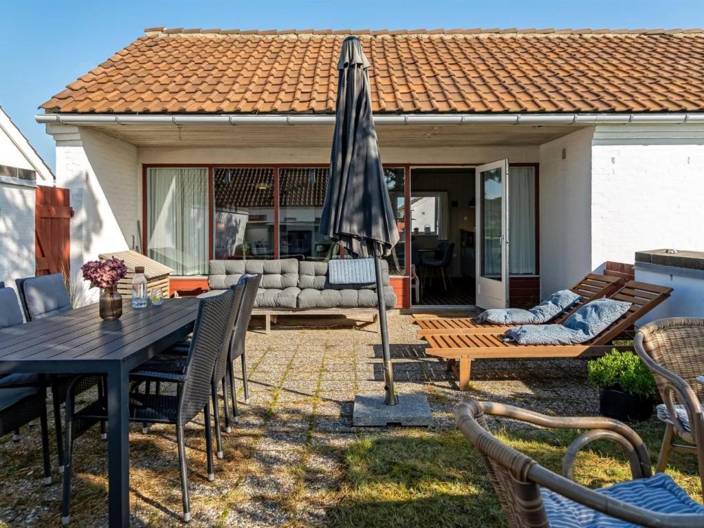 a patio with a table and an umbrella at Apartment Enwald - 700m from the sea by Interhome in Rødhus