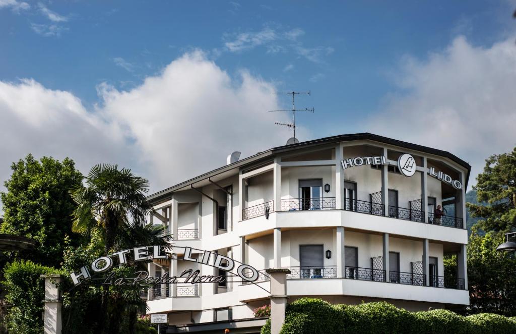 a white hotel with a sign in front of it at Hotel Lido La Perla Nera in Stresa