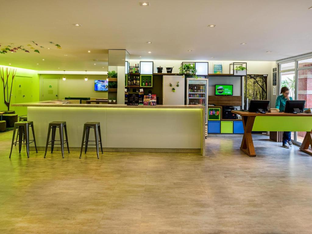 a room with a bar with stools and a person using a laptop at ibis Styles Curitiba Centro Civico in Curitiba