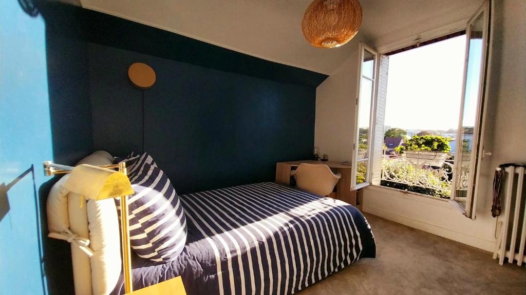 a bedroom with a bed with a blue accent wall at Chambres dans une maison de charme au calme en bord de Marne proche transports in Joinville-le-Pont