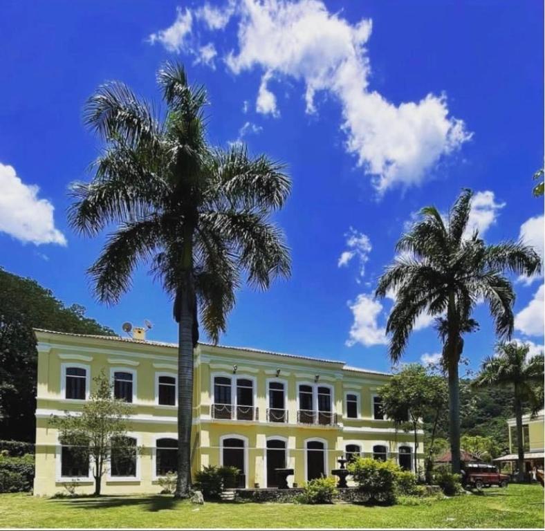 a building with two palm trees in front of it at Fazenda Neuchatel in Guaratinguetá