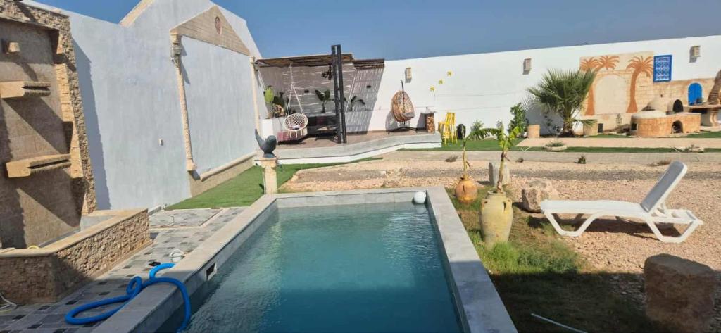 a swimming pool in the yard of a house at Dar Dalloula maison de vacances espace detente in Shanīnī