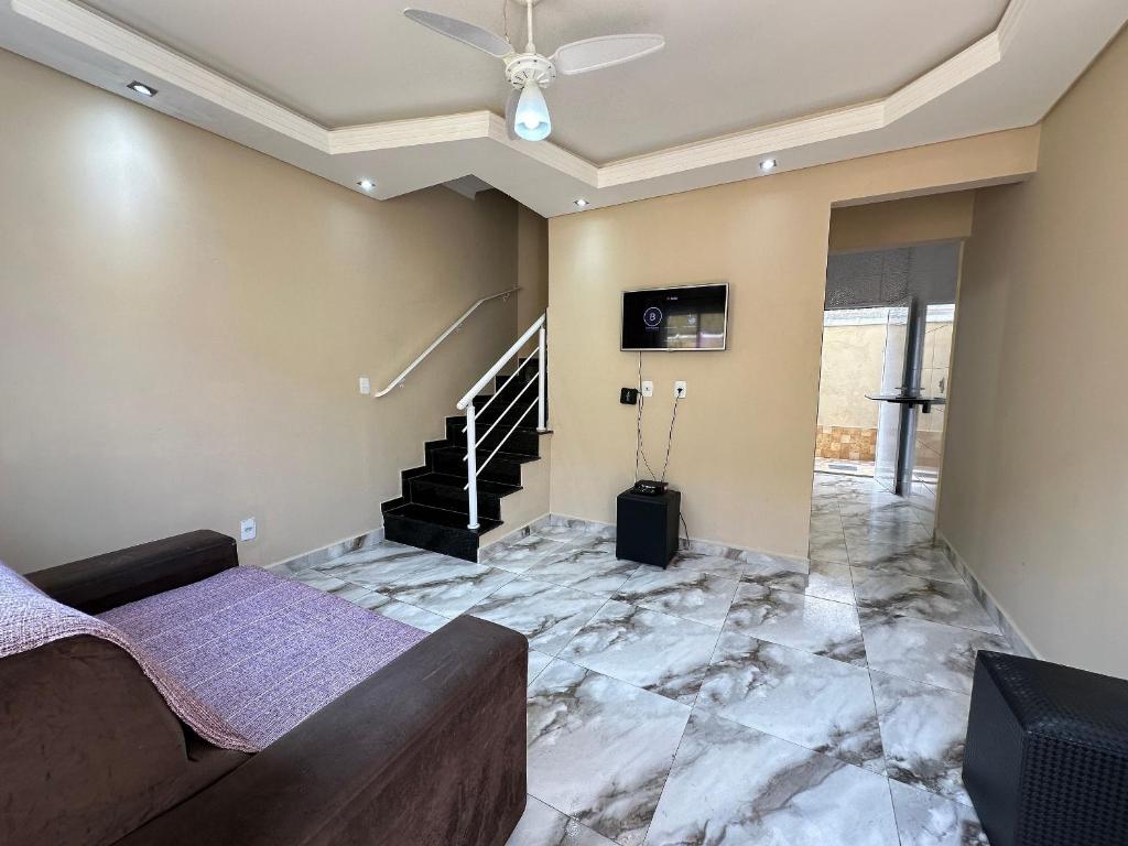 een woonkamer met een bank en een plafondventilator bij Estadia no Caiçara com Praia a 150m! in Vila Balneária