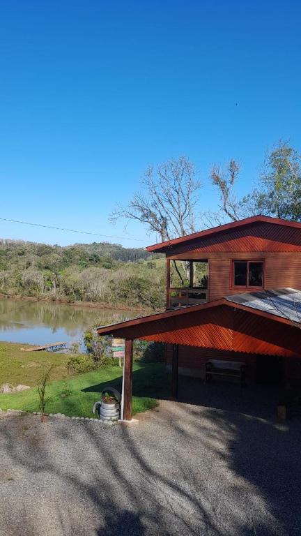 a wooden house with a lake in the background at Casa rústica às margens do lago in Maximiliano de Almeida