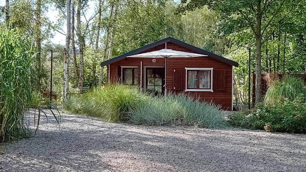 a small cabin with an umbrella in a forest at Domek nad jeziorem Strykowskim in Sapowice