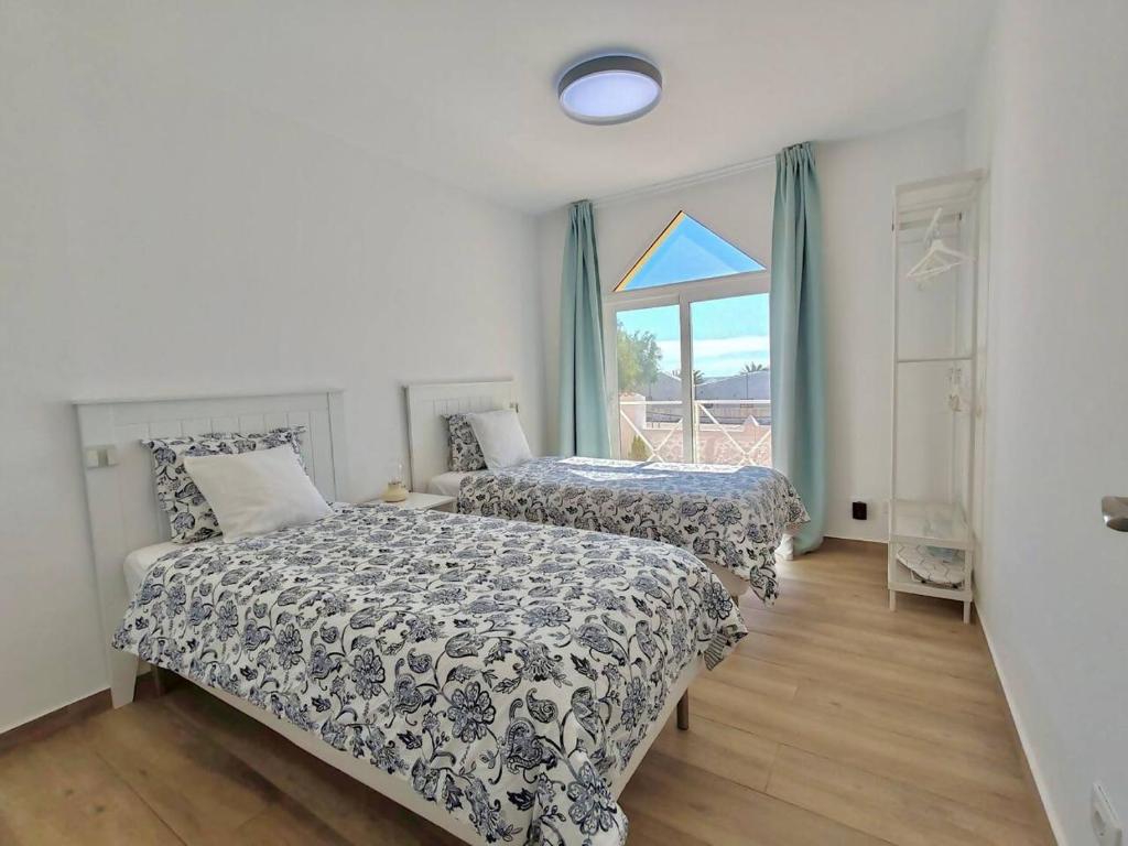 a bedroom with two beds and a window at Casa Min26 in Caleta De Fuste