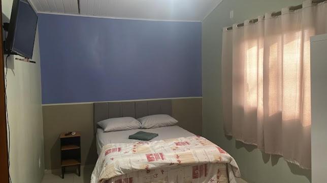 una camera da letto con un letto con una parete blu di Hotel Juan William em Brasilândia a Panorama