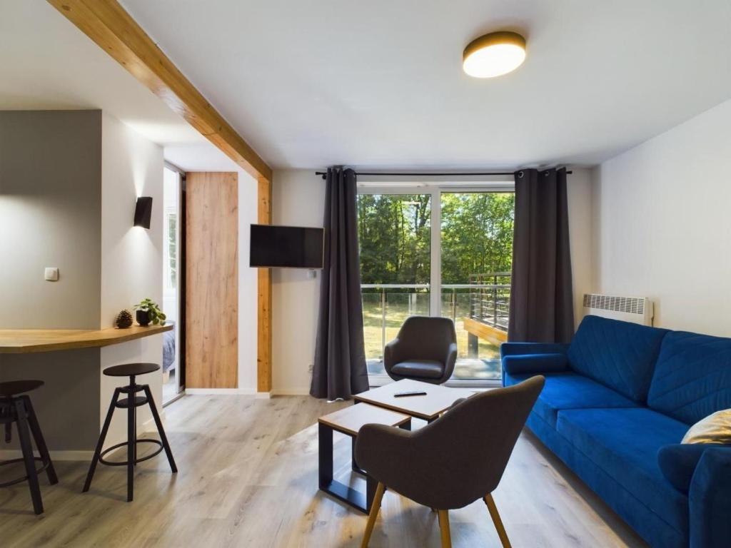 ein Wohnzimmer mit einem blauen Sofa und einem Tisch in der Unterkunft Apartamenty Dąbrówka luxury - w lesie, parking in Jelenia Góra