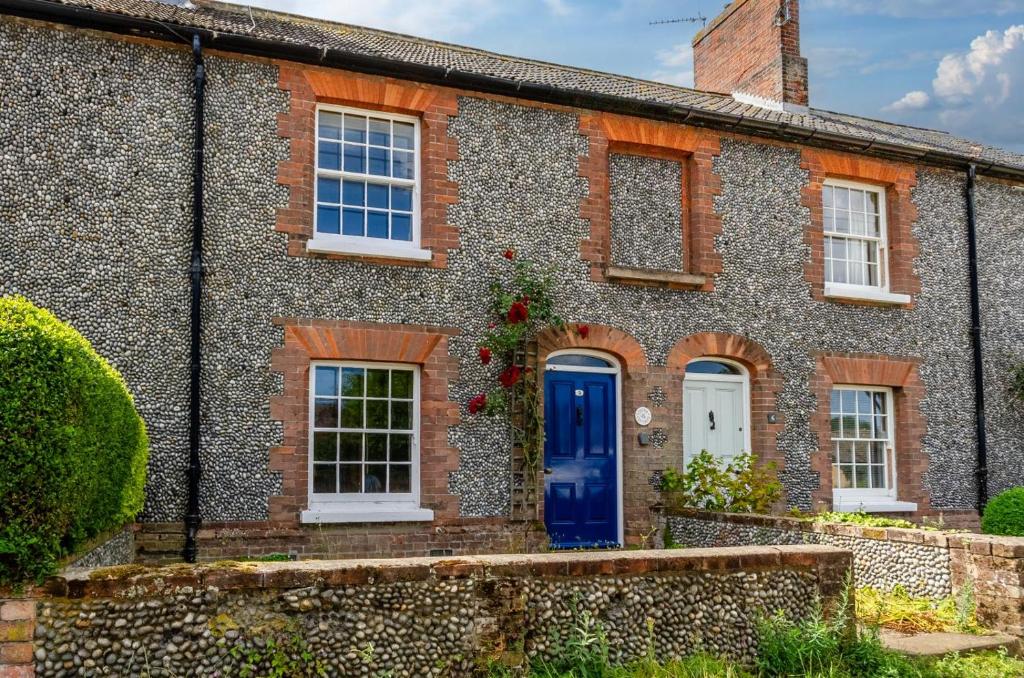 an old brick house with a blue door at China Cottage in Weybourne