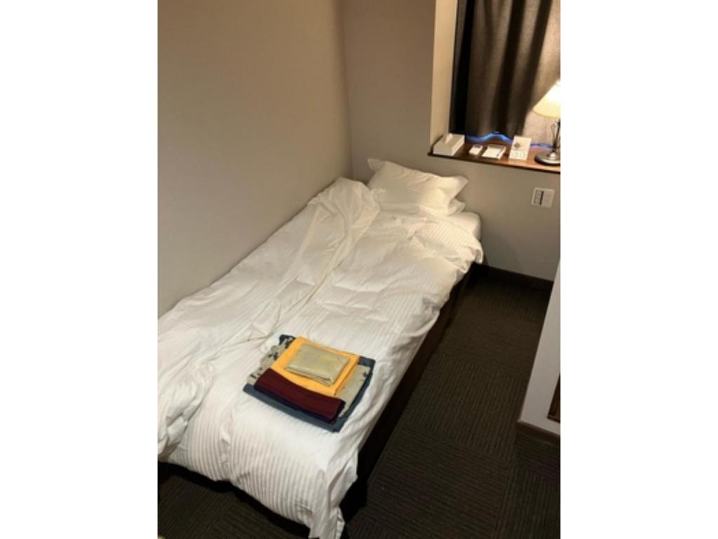 a room with a bed with a book on it at Yahatakan - Vacation STAY 32424v in Sado