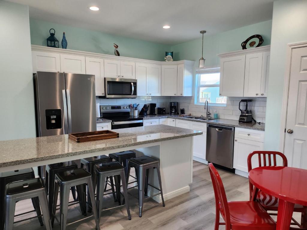 eine Küche mit weißen Schränken und eine Insel mit Barhockern in der Unterkunft Escape to the beach with pets &kids in Bolivar Peninsula