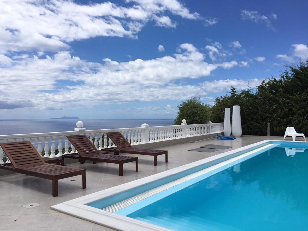 einen Pool auf einem Balkon mit Stühlen und Meerblick in der Unterkunft Golden View Residence in Dhërmi
