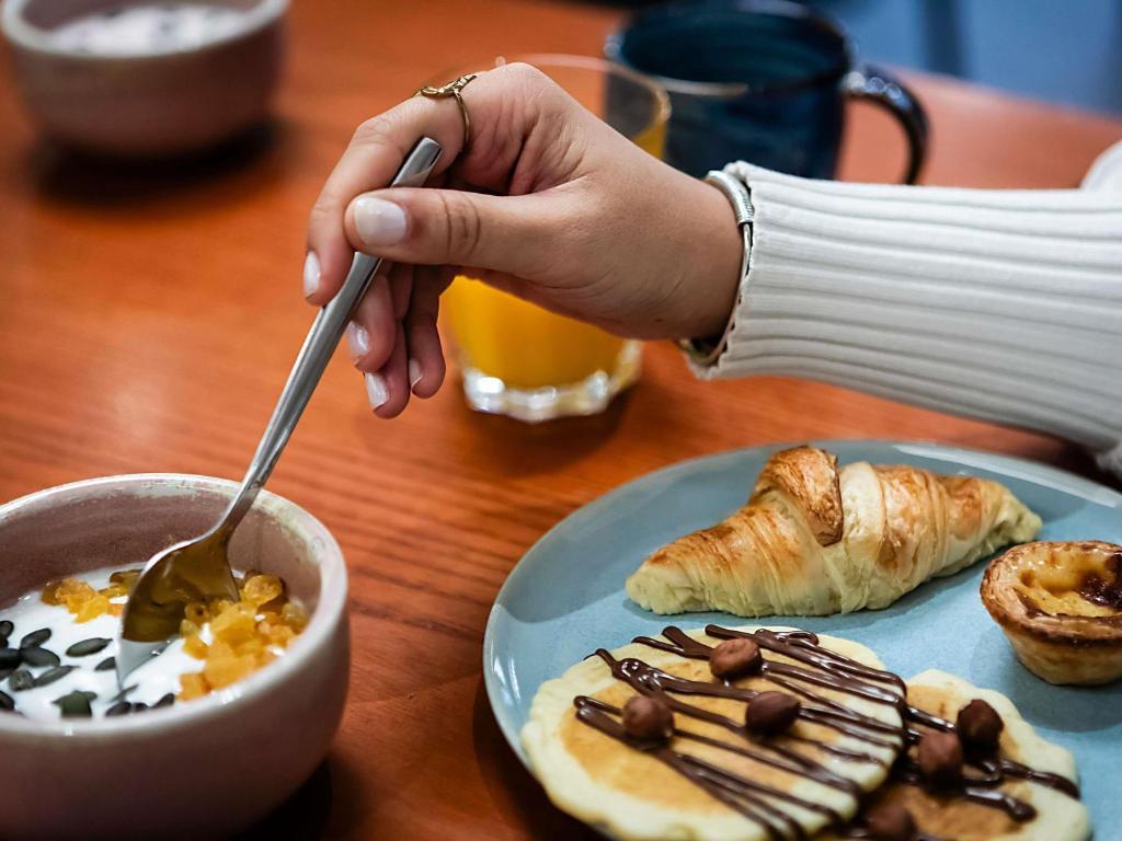 een persoon die voedsel eet met een lepel en een bord voedsel bij Hotel Mercure Lisboa in Lissabon