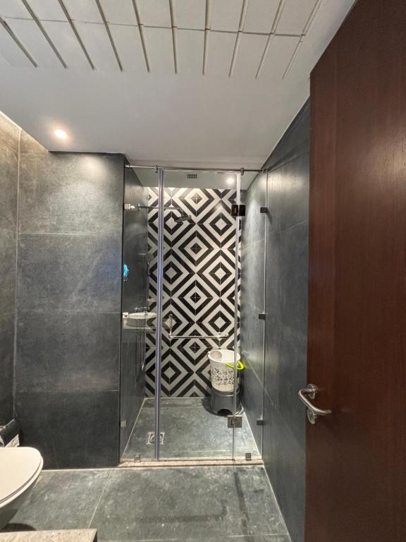 a shower with a glass door in a bathroom at Vaelora Stay Modern & Cozy Studio Apartment in Ghaziabad