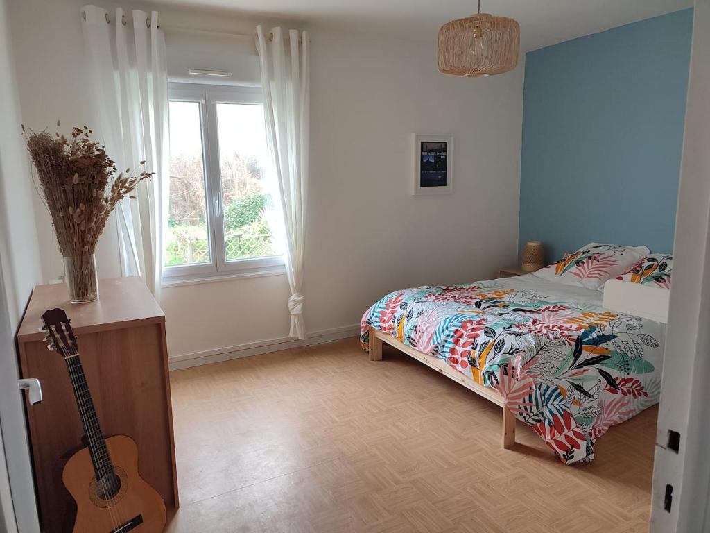 a bedroom with a bed and a guitar in it at Ty Pagaille Apartment and garden with terrace in Groix
