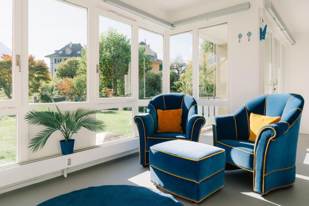 two blue chairs in a room with windows at Apartment Baytrail in Seenähe in Spiez
