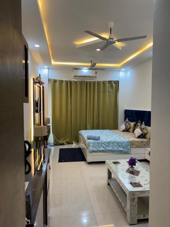 a living room with a bed and a table at Premium Studio Apartment near Gaur City Mall, Noida Extension in Ghaziabad