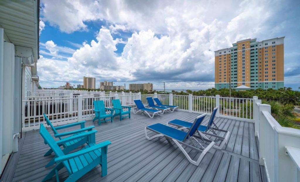 eine Terrasse mit blauen Stühlen und einem weißen Zaun in der Unterkunft Holiday Beach at Thomas Drive in Panama City Beach