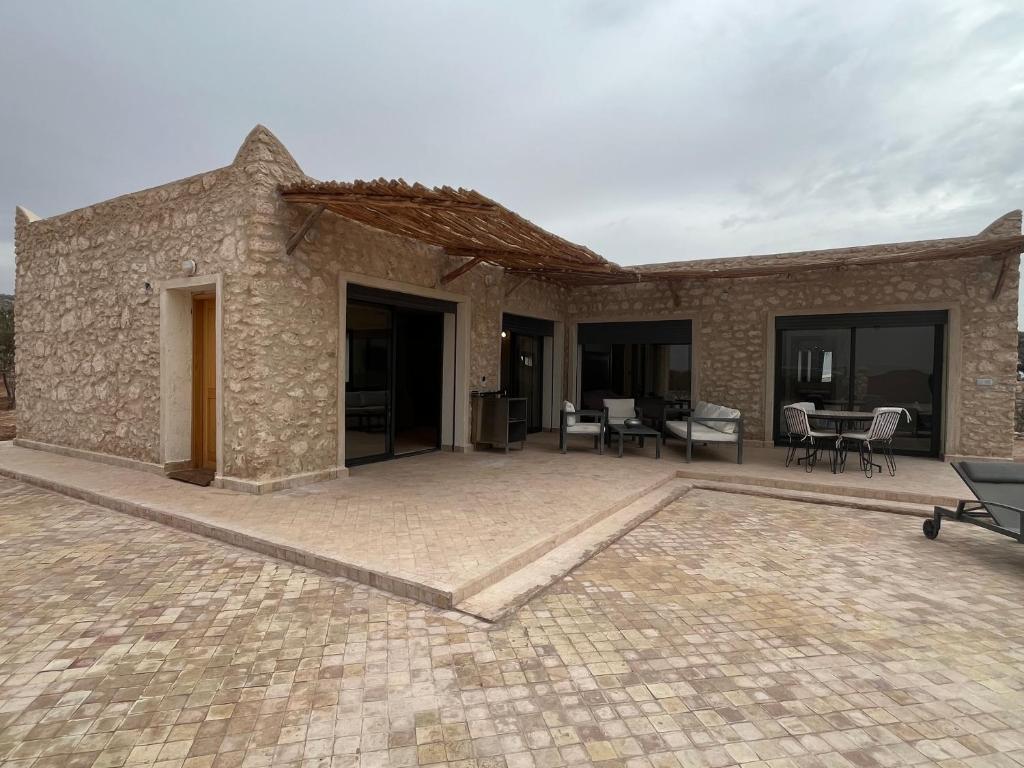 a stone house with a patio with tables and chairs at Dar'S in Moulay Douraïne