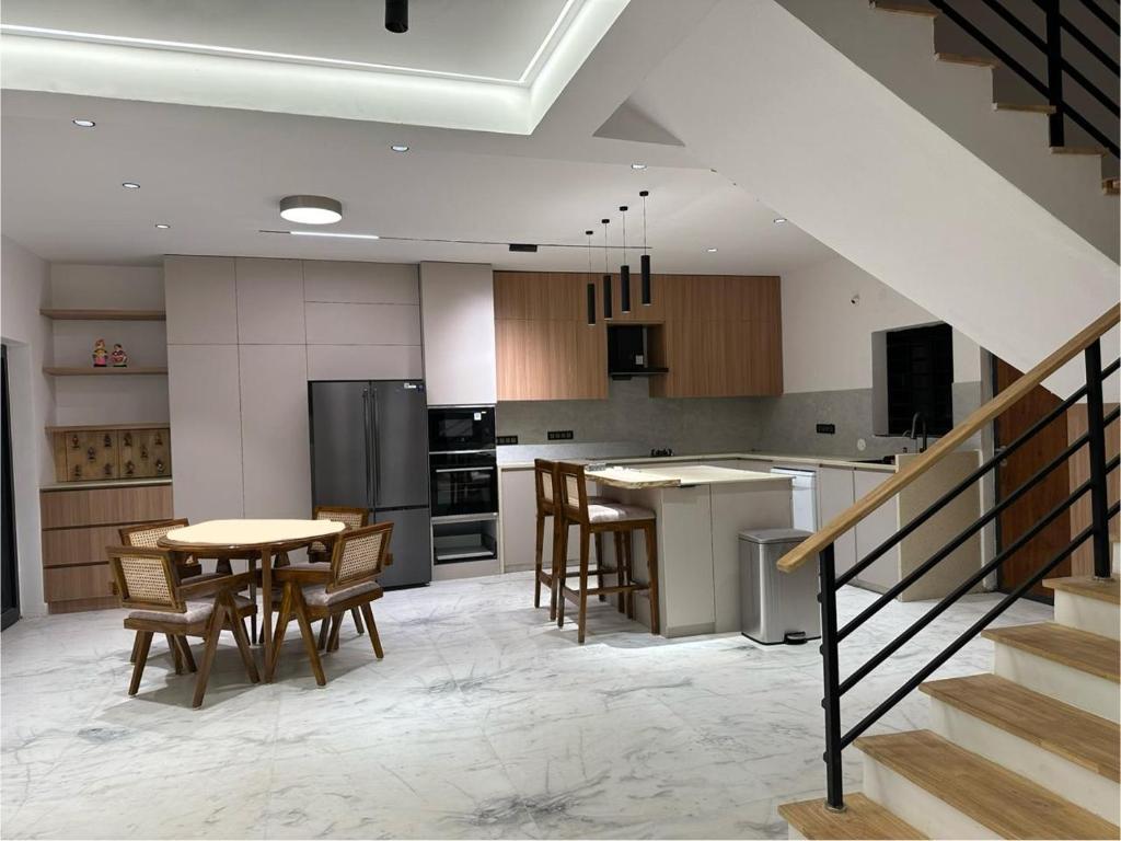 a kitchen with a table and chairs and a kitchen with a staircase at Luxe Villa in Sanikpuri, Hyderabad in Secunderabad