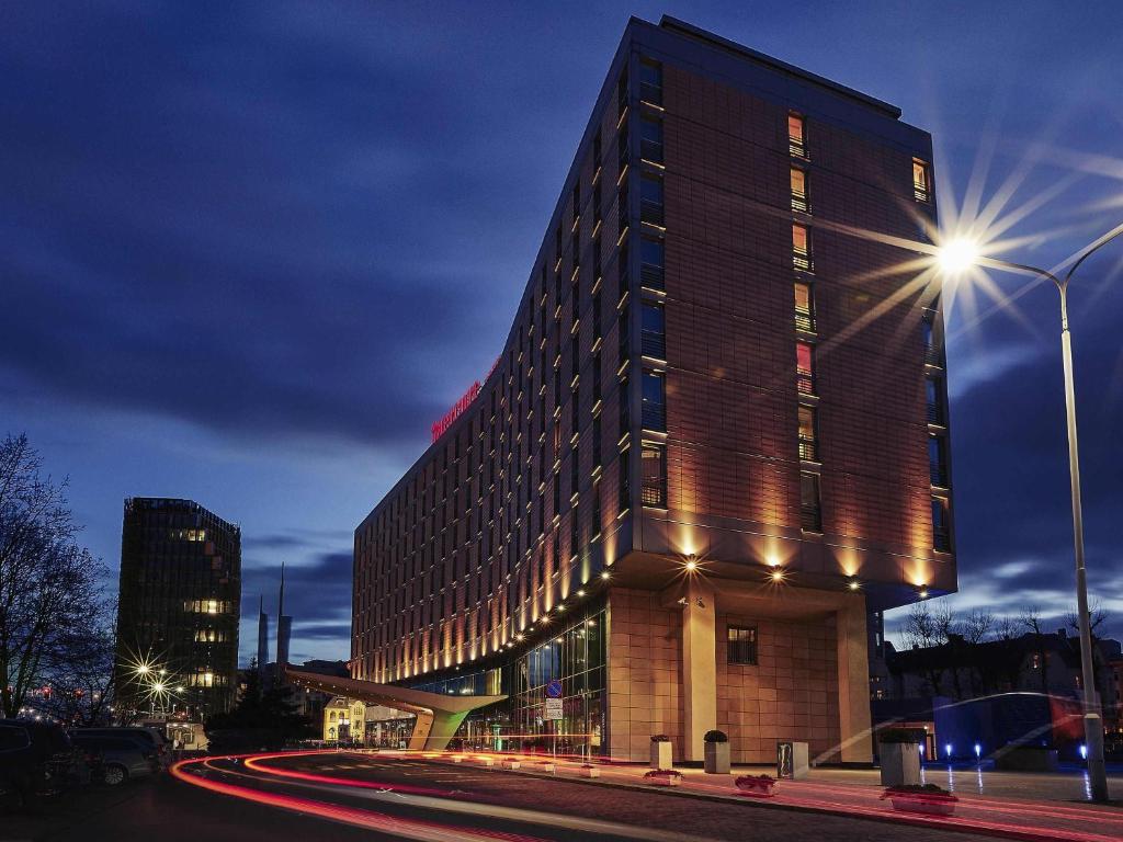 un grand bâtiment avec un éclairage de rue devant lui dans l'établissement Hotel Mercure Poznań Centrum, à Poznań