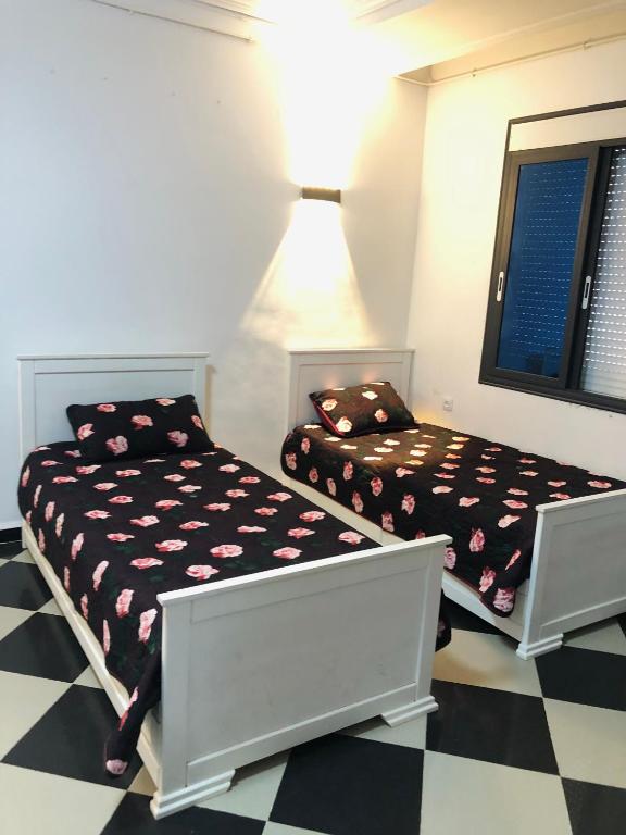 a bedroom with two beds and a checkered floor at Studio elkala in El Kala