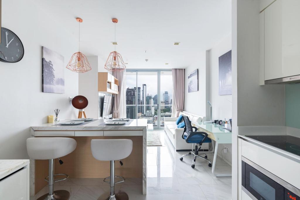 een witte keuken met een bureau en stoelen bij The Pinnacle Sukhumvit 11 by LeFoyer in Bangkok