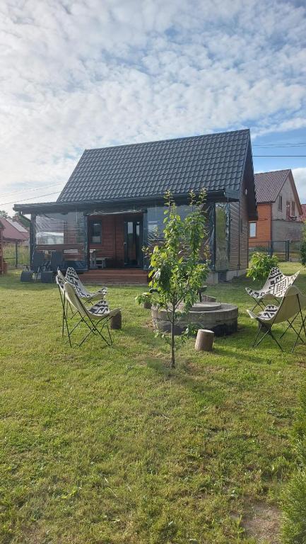 a house with two lawn chairs in front of it at Uroczy domek nad Gilem in Miłomłyn