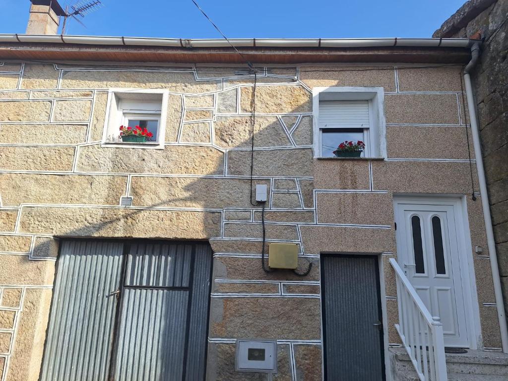 a brick building with two windows with flowers in them at Casa María in Baltar