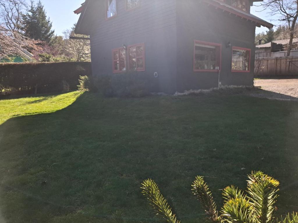 Una casa con un césped verde delante de ella. en Los Panguis, en Villa La Angostura