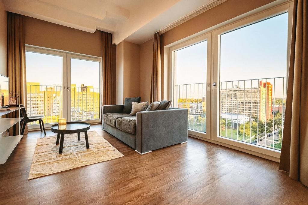 a living room with a couch and large windows at Homely! Skyview 2-Room Apartment, Airport, Fair, Rooftop, Gym! in Frankfurt/Main