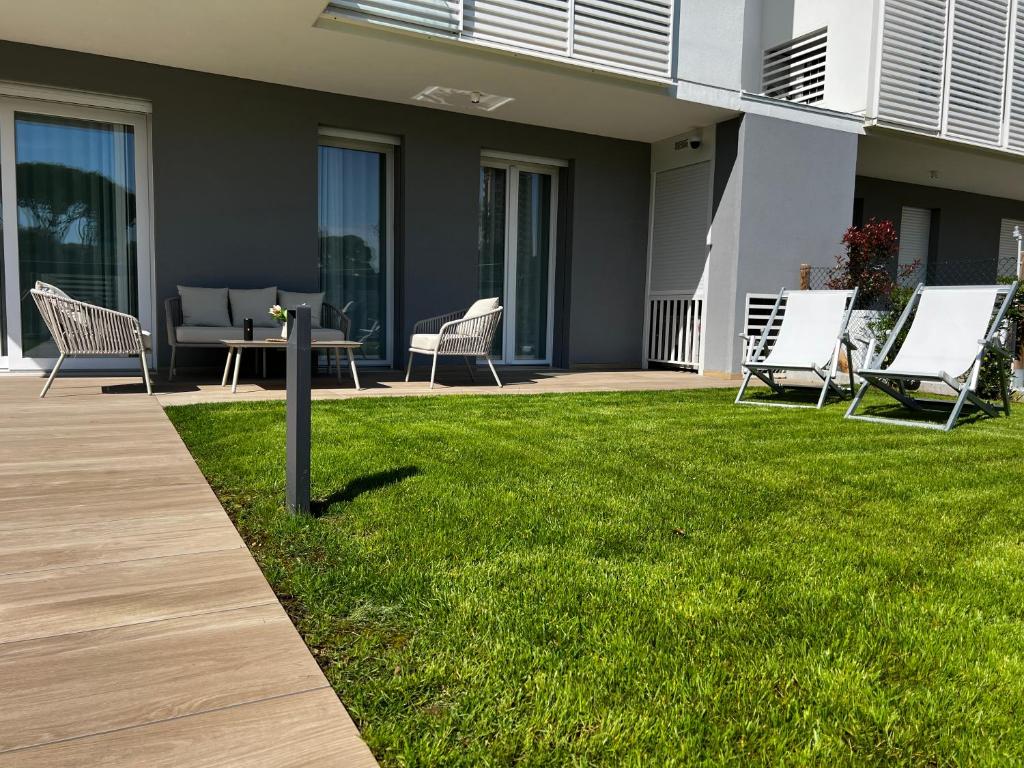 a group of chairs and a table on a lawn at Jesolo Pineta Fronte Mare - Jl Blue Apartments C5 in Lido di Jesolo