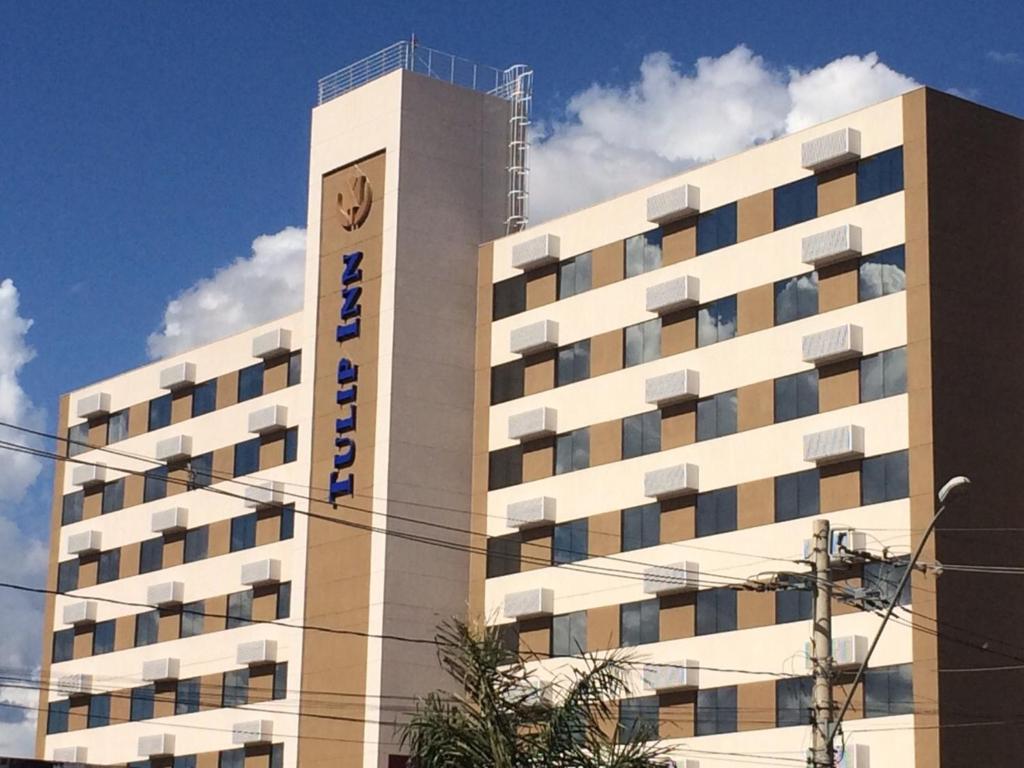 a large white building with a clock on it at Tulip Inn Sete Lagoas in Sete Lagoas