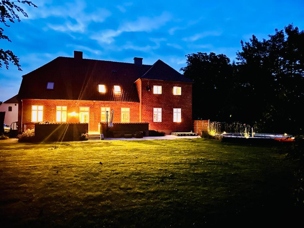 a house with lights on in a yard at night at Birkelund1927 in Dannemare