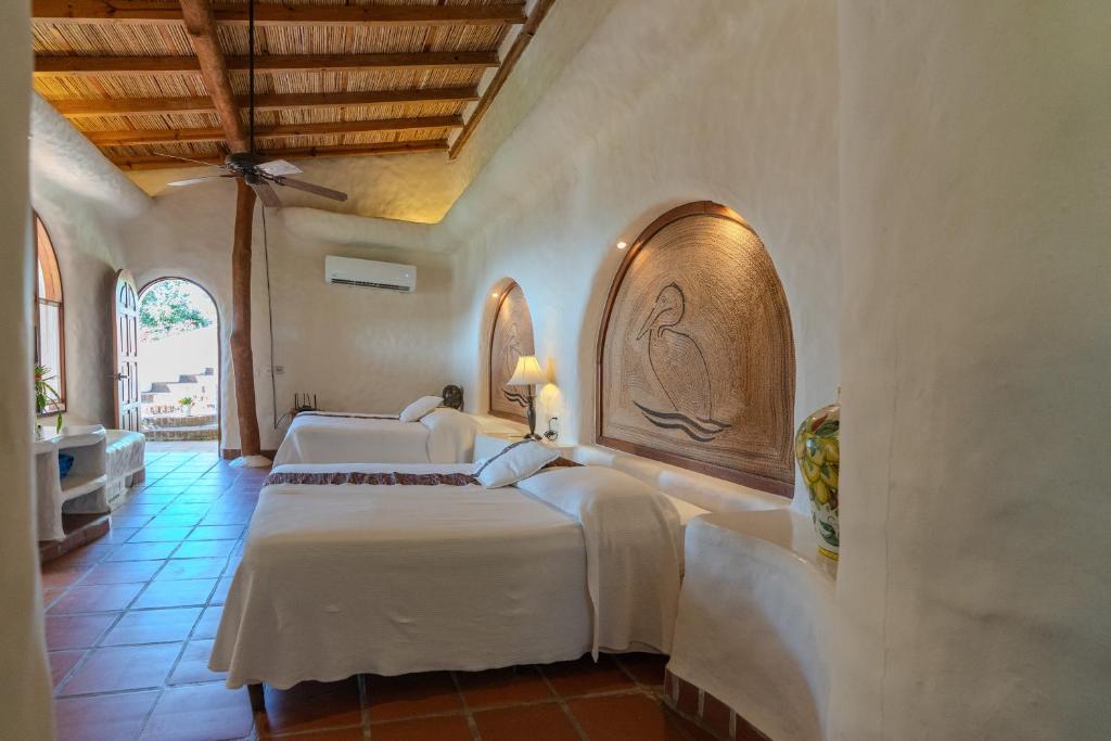 two beds in a room with white sheets at Pelican Eyes Hotel and Resort in San Juan del Sur