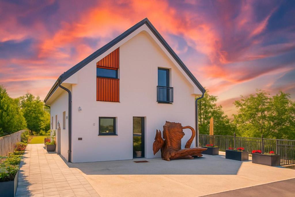 a white house with a cat statue in front of it at Wellness Villa Vinita in Sveti Jurij ob Ščavnici