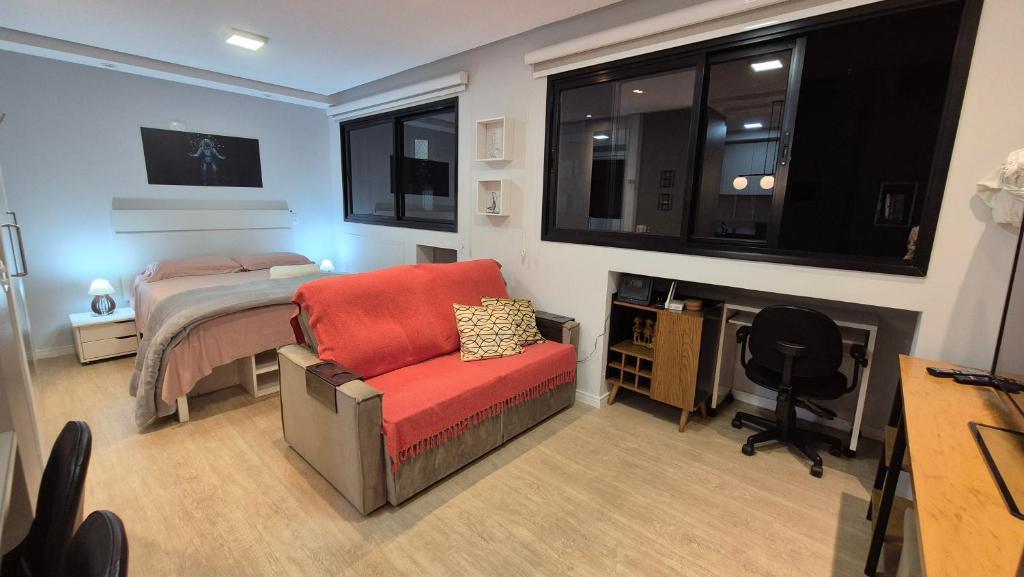 Un dormitorio con una cama, una silla y un escritorio. en Studio Aconchegante Jd Botânico, en Curitiba