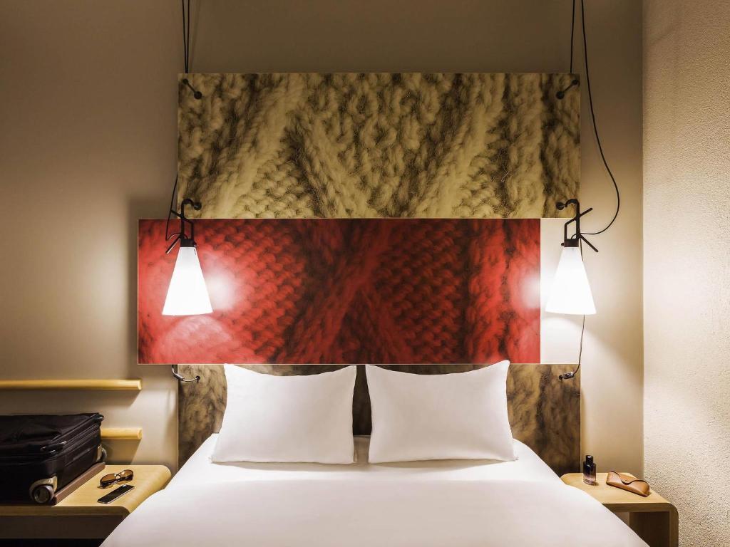 a bed with two white pillows and a painting above it at ibis Winterthur City in Winterthur