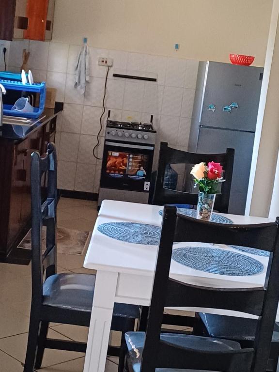 Il comprend une cuisine équipée d'une table avec deux chaises et d'un four. dans l'établissement Pebs one bedroom apartment, à Mombasa