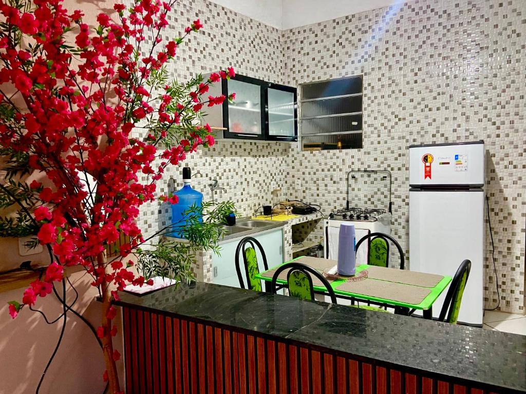 a kitchen with a table with red flowers in it at Meu aconchego - check-in e checkout flexível in Belém
