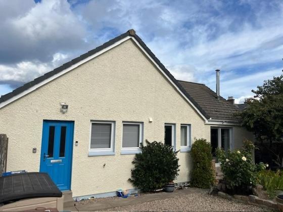 a white house with a blue door at Lighthouse Cottage Cullen in Cullen