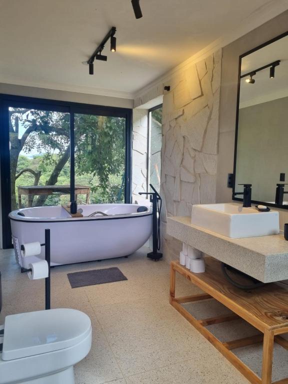 a bathroom with a tub and two sinks and a toilet at Chalé Alto padrão in Brazópolis