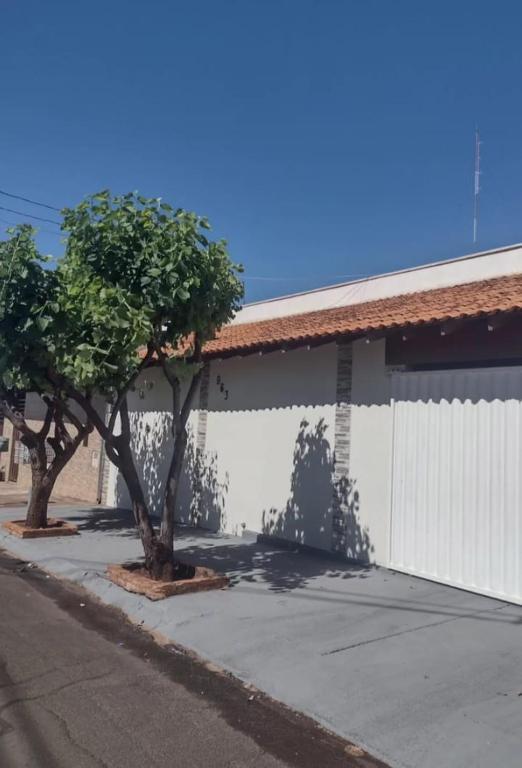 two trees in front of a white building at Casa de temporada lus delicatte in Olímpia