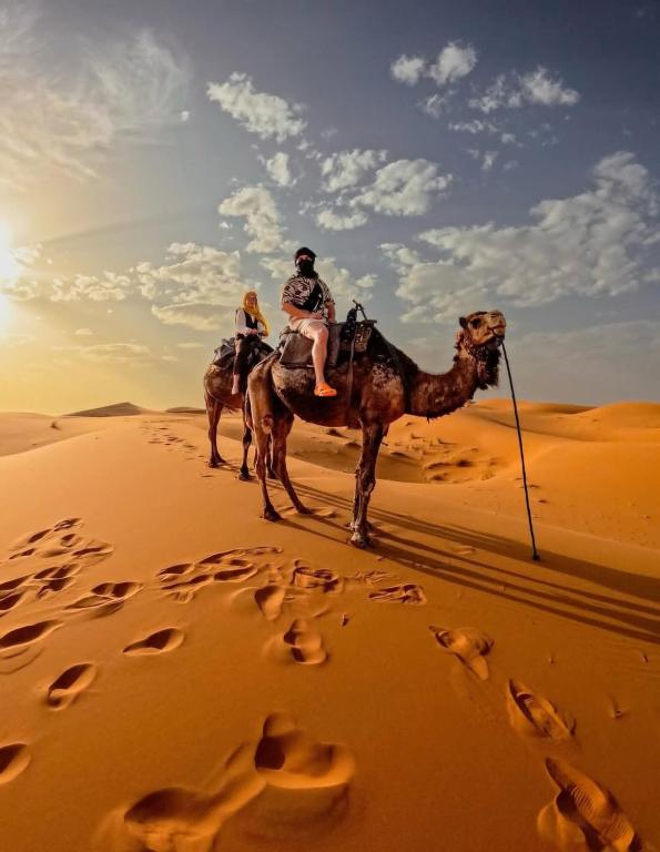 two people riding on a camel in the desert at Sahara Bedouin camp in Mhamid