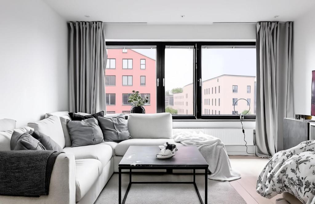 a living room with a white couch and a large window at Aurora Luxe Apartment Växjö Near Vida Arena in Växjö