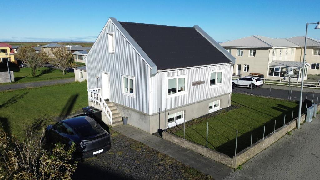 a white house with a car parked in front of it at Holiday Home in town Eyrarbakki South of Iceland - Birta Rentals in Eyrarbakki
