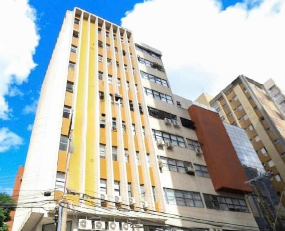 a tall yellow and white building with buildings at 13 Studio completo, perto TRT, Smartfit, Life Center, cozinha in Belo Horizonte