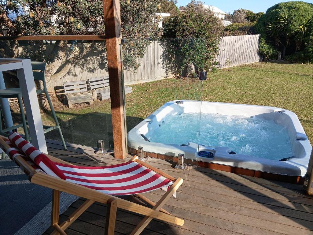 a deck with a chair and a hot tub at Good Vibes at Surf Beach with Spa in Surf Beach
