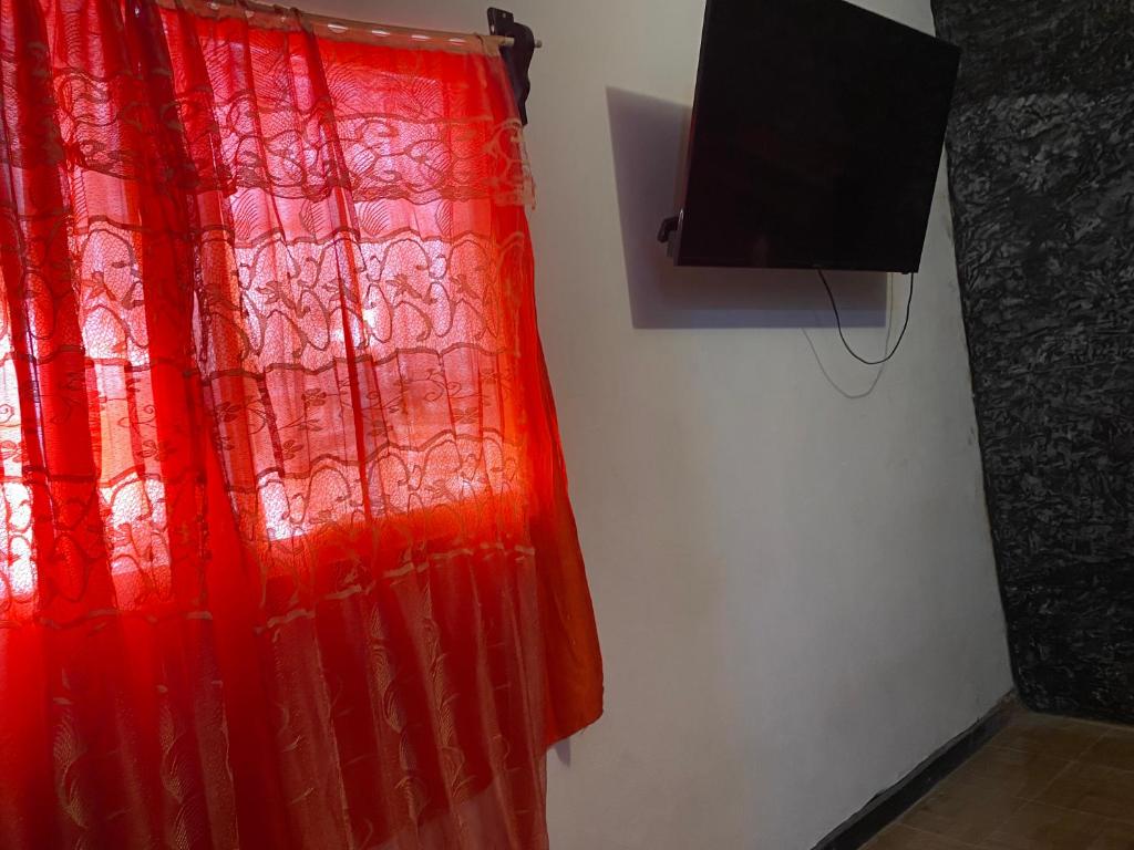 a red curtain on a wall next to a television at Bonita habitación a 3 min Del Word Trade Center in Veracruz