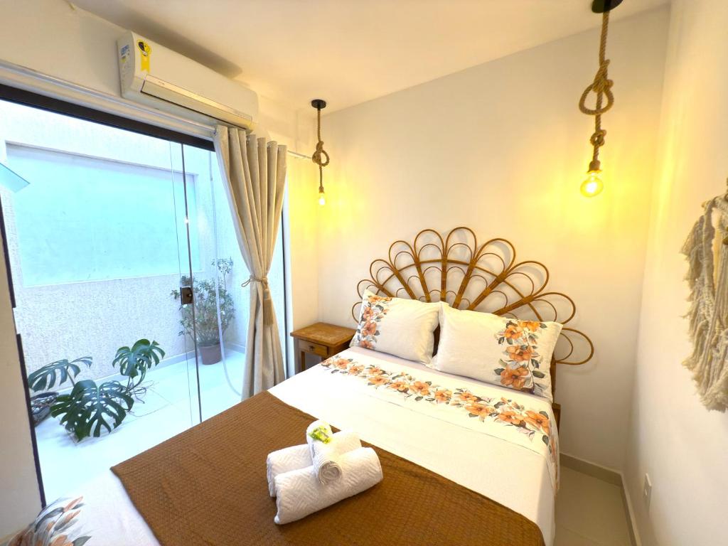 une chambre avec un lit avec une grande fenêtre dans l'établissement Flat Centro de Buzios, à Búzios